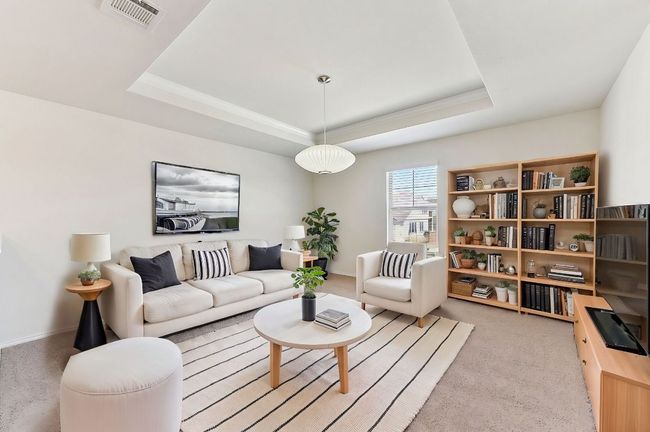 Carpeted living area featuring baseboards, a tray ceiling, and visible vents | Image 14