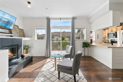 The open great room floor plan features stylish LVP flooring, a cozy fireplace for relaxation, and a private balcony, creating the perfect space for comfort and entertaining. | Image 2