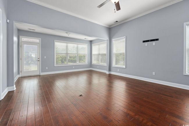 Unfurnished living room featuring visible vents, ceiling fan, baseboards, ornamental molding, and dark wood finished floors | Image 15