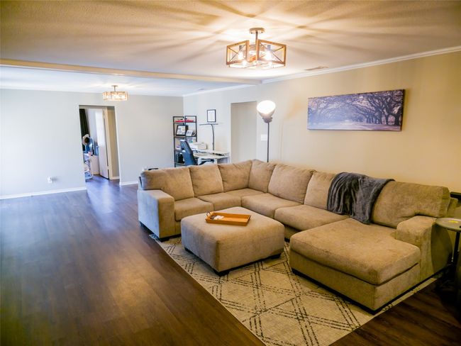 Living area with a chandelier, wood finished floors, baseboards, and crown molding | Image 6