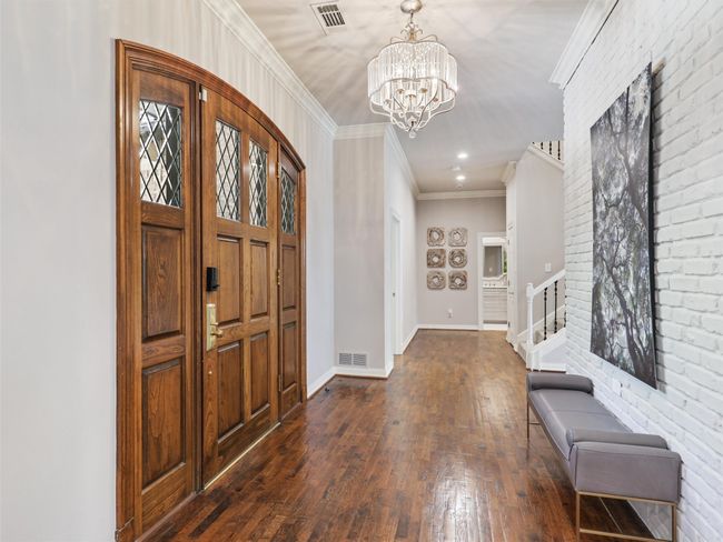 Entryway featuring dark wood-style flooring, a chandelier, ornamental molding, stairway, and recessed lighting | Image 6