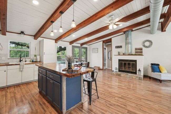 Kitchen with wood counters, a sink, a kitchen bar, light wood-style flooring, and open floor plan | Image 14
