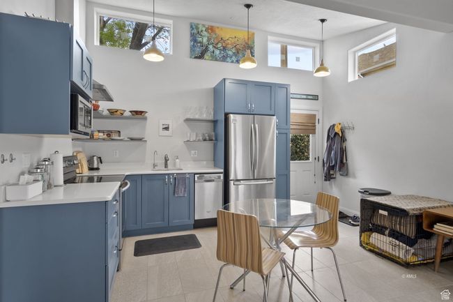Kitchen with excellent cabinetry, white countertops, a healthy amount of sunlight, open shelves, and stainless steel appliances | Image 4