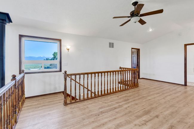 Open area featuring vaulted ceiling, light wood-style floors, baseboards, and a ceiling fan | Image 29