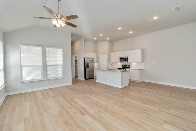 Kitchen with visible vents, appliances with stainless steel finishes, open floor plan, a kitchen island with sink, and a sink | Image 7