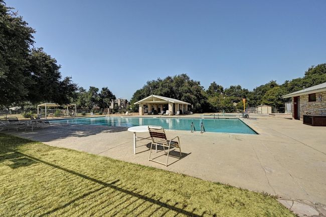 Community pool with a patio, a storage shed, and view of wooded area | Image 33