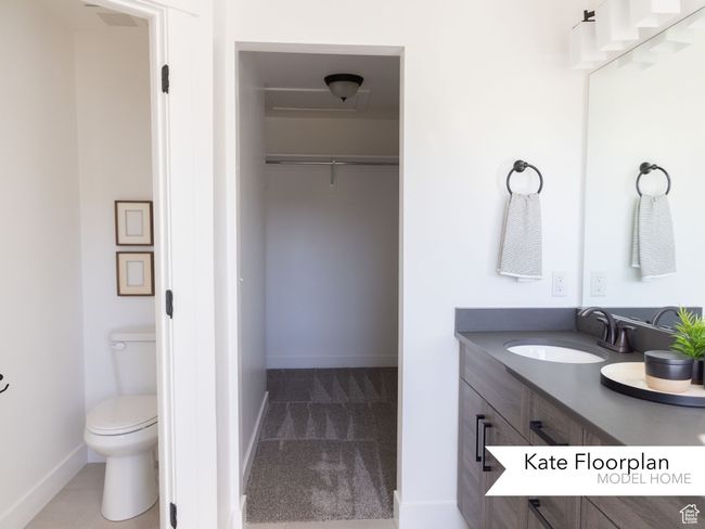 Full bathroom featuring vanity, baseboards, a spacious closet, and toilet | Image 12