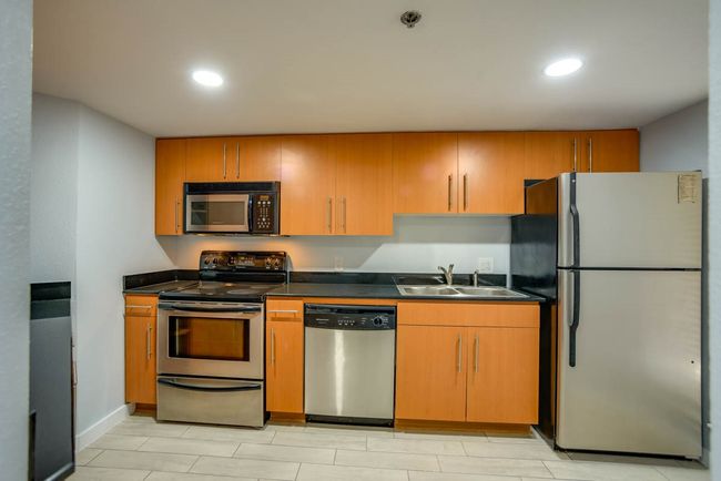 Kitchen featuring stainless steel appliances, dark countertops, recessed lighting, and brown cabinetry | Image 4