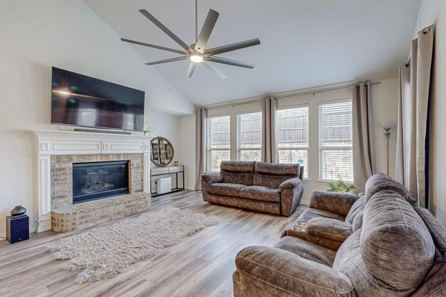 Living area featuring ceiling fan, wood finished floors, a fireplace, and high vaulted ceiling | Image 24