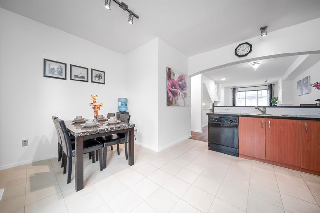 Kitchen featuring arched walkways, dishwasher, a sink, dark countertops, and baseboards | Image 12