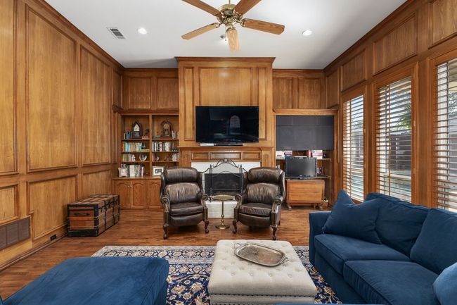 Living room with ceiling fan, wooden walls, and wood finished floors | Image 12