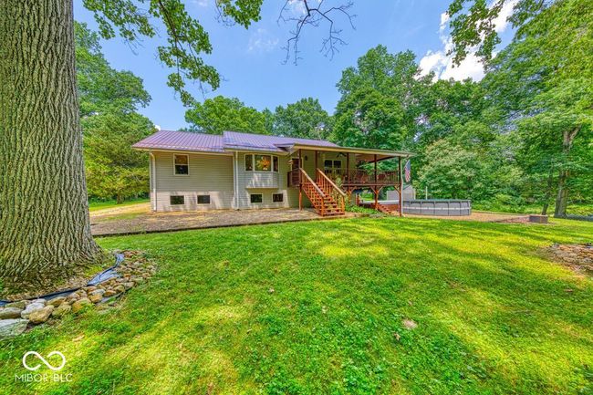 back of property featuring stairs, a lawn, a metal roof, and a swimming pool | Image 54