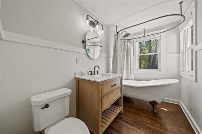 Full bath featuring a shower with shower curtain, toilet, wood finished floors, vanity, and a freestanding bath | Image 20