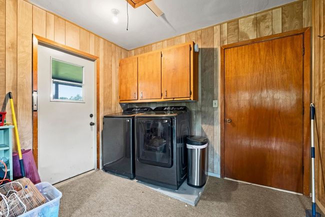 Laundry area featuring cabinet space, washing machine and clothes dryer, carpet, and wooden walls | Image 22