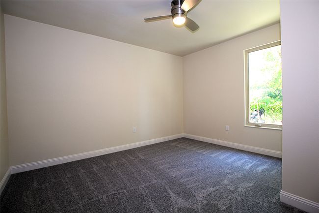 Unfurnished room with ceiling fan, dark carpet, and baseboards | Image 8
