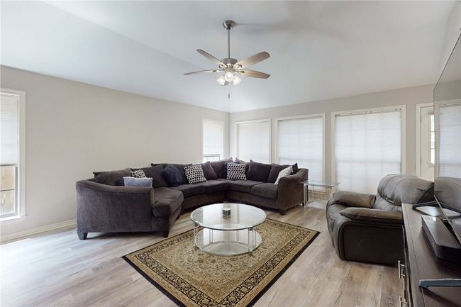 Living area featuring light wood-style flooring, a ceiling fan, vaulted ceiling, and baseboards | Image 5