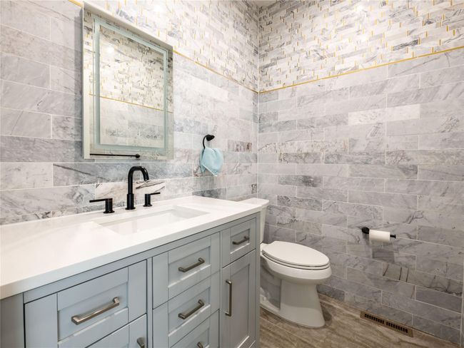 Bathroom with tile walls, visible vents, vanity, and toilet | Image 12
