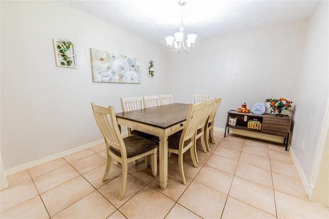 This is a bright dining room that features tile flooring, neutral walls and a modern chandelier. | Image 12