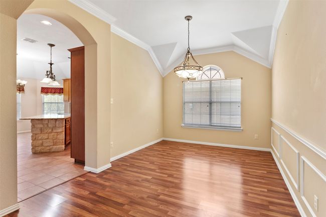 Empty room with wood finished floors, arched walkways, crown molding, lofted ceiling, and baseboards | Image 25
