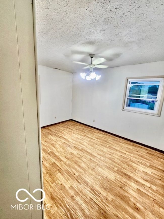 unfurnished room with baseboards, wood finished floors, a ceiling fan, and a textured ceiling | Image 10