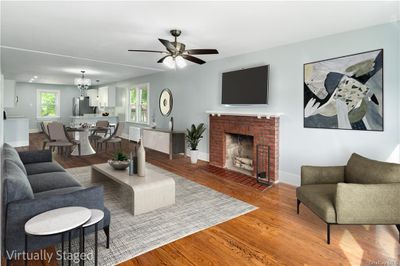 Living room with hardwood / wood-style flooring, ceiling fan with notable chandelier, and a fireplace | Image 2