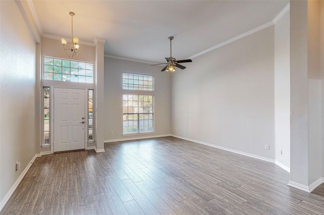 Entryway featuring wood finished floors, a chandelier, ornamental molding, ceiling fan, and baseboards | Image 7