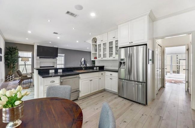 Kitchen featuring a sink, stainless steel fridge, a peninsula, dishwashing machine, and light wood-type flooring | Image 15