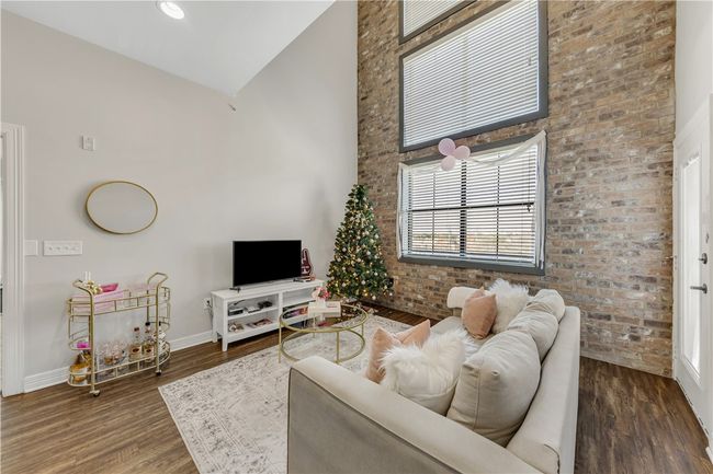 Living room with dark wood-type flooring, brick wall, and a high ceiling | Image 19