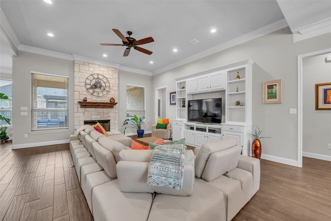 Living area with a ceiling fan, wood finished floors, crown molding, recessed lighting, and baseboards | Image 9