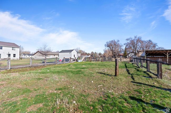 View of yard featuring a residential view, an outdoor structure, and fence | Image 7