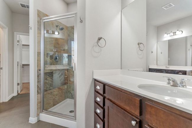 Full bathroom featuring a shower stall, tile patterned floors, visible vents, and vanity | Image 24