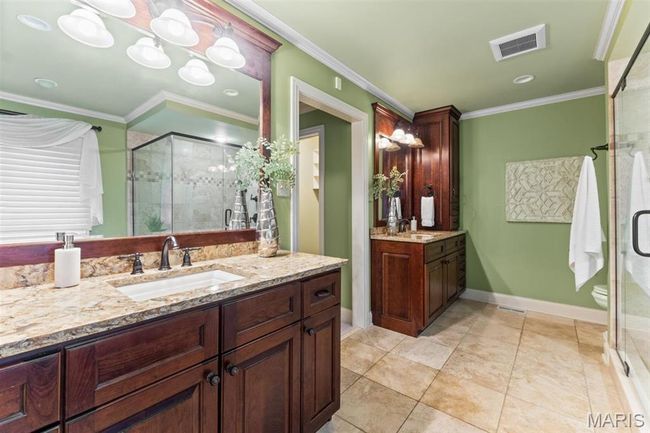 Full bathroom featuring a shower stall, two vanities, and crown molding | Image 41