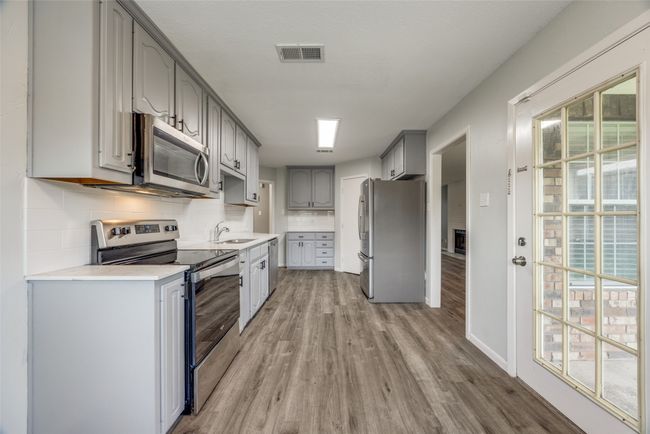 Kitchen with stainless steel appliances, gray cabinetry, light wood-type flooring, and healthy amount of natural light | Image 6