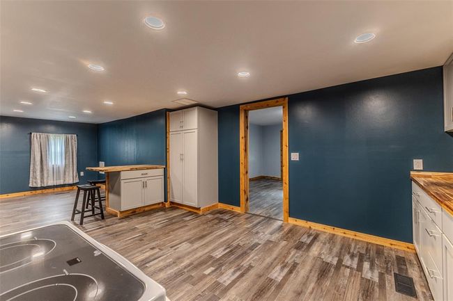 Kitchen featuring wood counters, light wood finished floors, baseboards, range with electric stovetop, and white cabinetry | Image 13