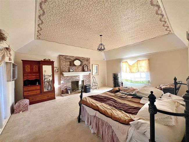 Primary bedroom featuring a cozy fireplace and a charming sitting area. | Image 11