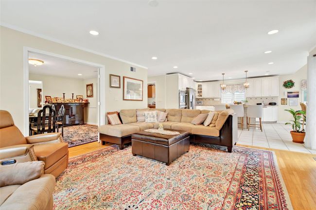 Living room with light wood finished floors, recessed lighting, crown molding, and baseboards | Image 13