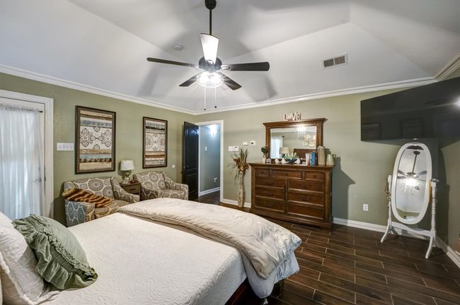 Bedroom with baseboards, ornamental molding, a ceiling fan, visible vents, and wood tiled floor | Image 23