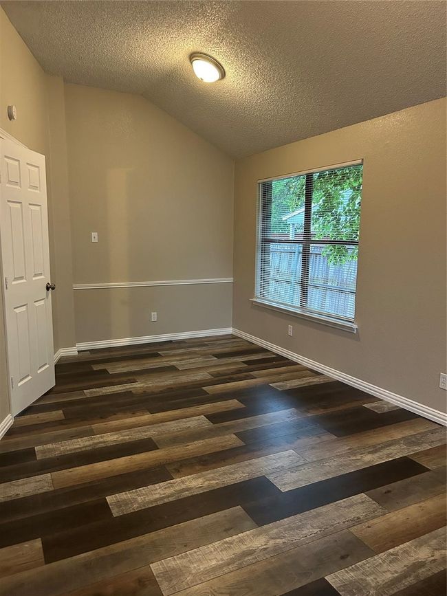 Unfurnished room featuring wood finished floors, lofted ceiling, and a textured ceiling | Image 19