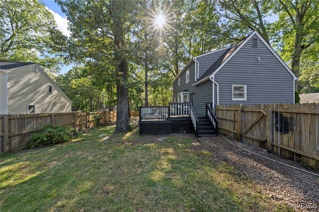 Fenced backyard featuring a wooden deck and view of scattered trees | Image 40