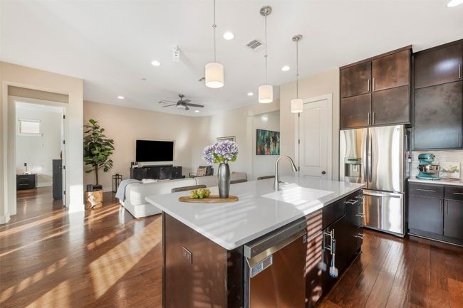 Kitchen with stainless steel appliances, dark wood-style floors, light countertops, hanging light fixtures, and dark brown cabinetry | Image 27
