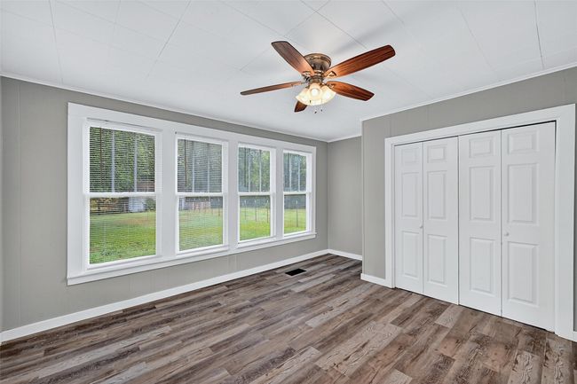 Unfurnished bedroom featuring wood finished floors, ornamental molding, a closet, and a ceiling fan | Image 14