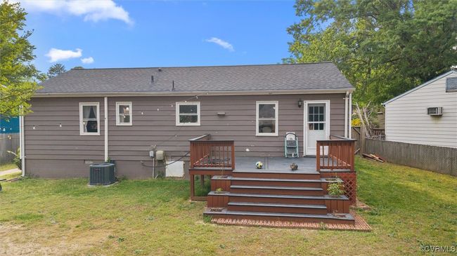 Rear view of house with central air condition unit, a shingled roof, a lawn, a deck, and fence | Image 38