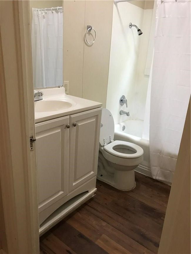 Bathroom featuring wood finished floors, vanity, and shower / tub combo | Image 8