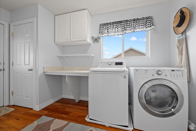 Laundry area with cabinet space, baseboards, separate washer and dryer, and wood finished floors | Image 19