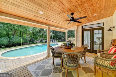 View of pool from covered deck with ceiling fan. | Image 3