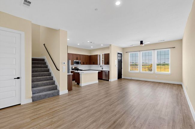 Unfurnished living room with light wood-type flooring, stairway, recessed lighting, and ceiling fan | Image 6