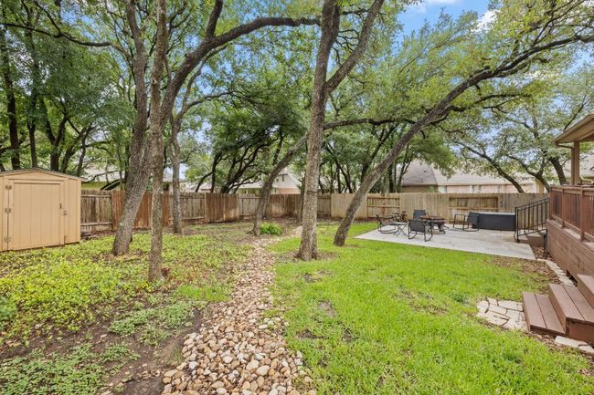 Fenced backyard with a storage unit, a patio area, and an outdoor fire pit | Image 35
