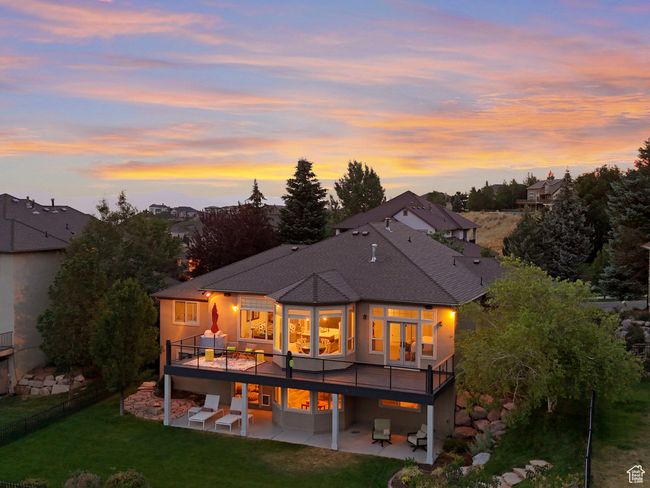 Back of property at dusk featuring a patio, a yard, a deck, roof with shingles, and french doors | Image 4