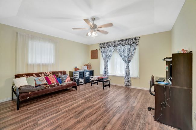 Living area featuring wood finished floors, ceiling fan, baseboards, and a tray ceiling | Image 19