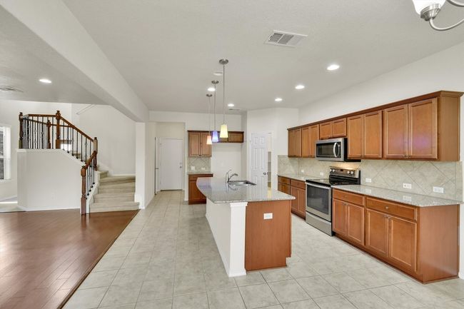 Kitchen with brown cabinets, visible vents, stainless steel appliances, and a sink | Image 9